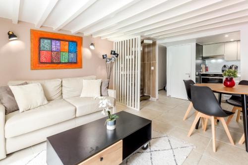 een woonkamer met een witte bank en een tafel bij Rivoli Vieille du temple in Parijs