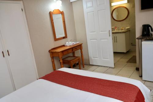 a bedroom with a bed and a table and a mirror at Shingalana Guest Lodge in Hazyview