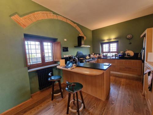 a kitchen with green walls and a counter with stools at Villetta dei Fagiani - B&B in Montauto
