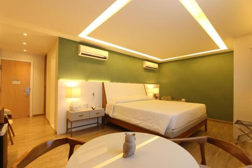 a bedroom with a bed and a table with chairs at Ajax Hoteis in Colatina