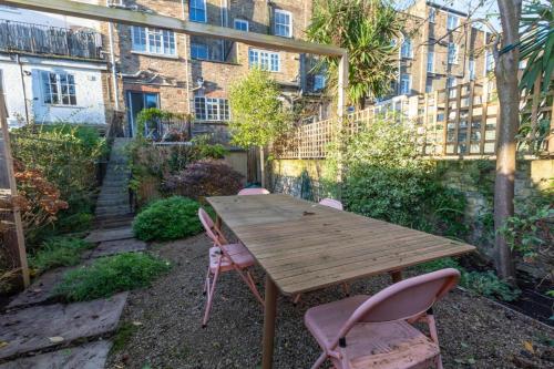 a wooden table and chairs in front of a building at Spacious 2BD Flat By Regents Park & Camden Town! in London