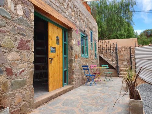 a stone house with a patio with chairs and a table at La Llama Negra in Tilcara