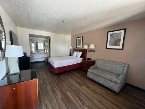 a hotel room with a bed and a chair at Fresno Inn in Fresno