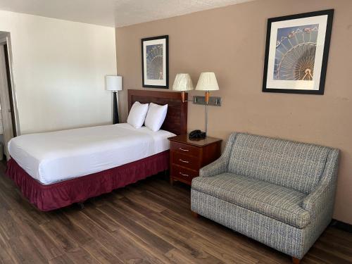 Habitación de hotel con cama y silla en Vagabond Inn Fresno, en Fresno