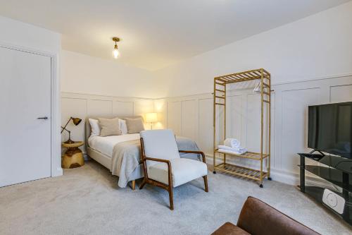Titsey的住宿－Oxted High St，一间卧室配有一张床、一把椅子和电视。