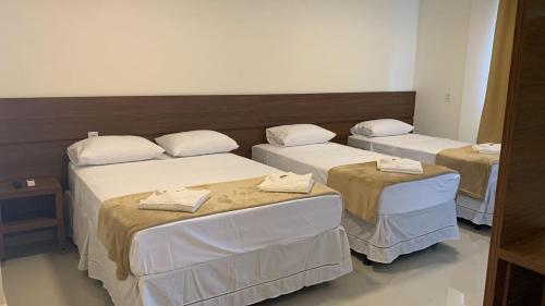 a room with three beds with white sheets at Lazzarus Hotel in Alexânia