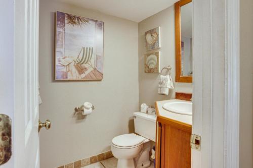 a bathroom with a toilet and a sink and a mirror at Harbor Island Condo with Deck - Steps to Beach! in Oceanmarsh Subdivision