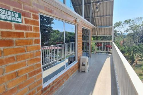 a brick building with a balcony with a window at COVEÑITAS MC1P2 Cabaña amplia y tranquila con Piscina tipo PLAYA, Máximo 32 Personas in Melgar