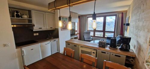 une cuisine avec des armoires blanches et une table avec des chaises dans l'établissement Résidence La Marelle et Le Rami - maeva Home - Appartement 2 pièces 7 personnes - Sélection MAE-1294, à La Plagne Tarentaise