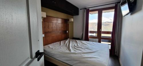 un petit lit dans une chambre avec une fenêtre dans l'établissement Résidence La Marelle et Le Rami - maeva Home - Appartement 2 pièces 7 personnes - Sélection MAE-1294, à La Plagne Tarentaise