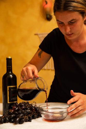 a woman pouring wine into a bowl with a bottle of wine at Hotel Galli in Livigno