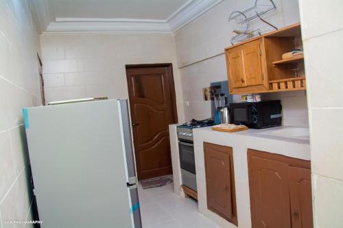 uma pequena cozinha com um frigorífico e um fogão em Oluwa-sheyi Apartment em Cotonou