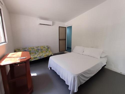 Punta Arena Beach Hostel في Playa Punta Arena: غرفة نوم بسرير وطاولة واريكة
