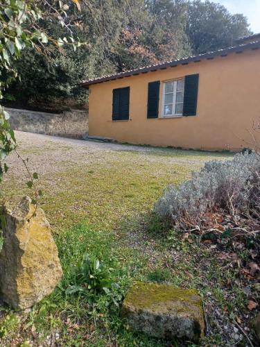 a house with black shuttered windows and a yard at Casa Asilo La Foce, Val d' Orcia, Pienza. in Pienza