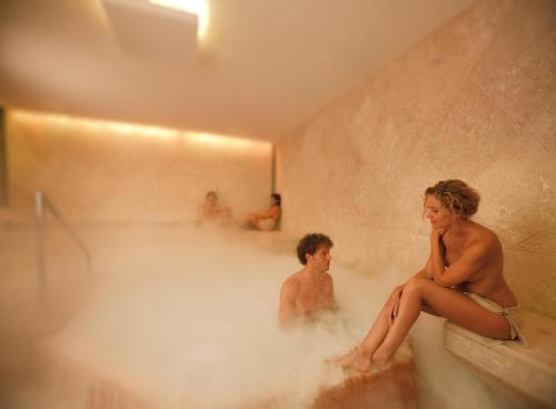 un homme et une femme assis dans un bain à remous dans l'établissement Albergo Le Terme, à Bagno Vignoni