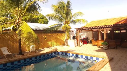 a swimming pool in front of a house with palm trees at Reverie in Willemstad