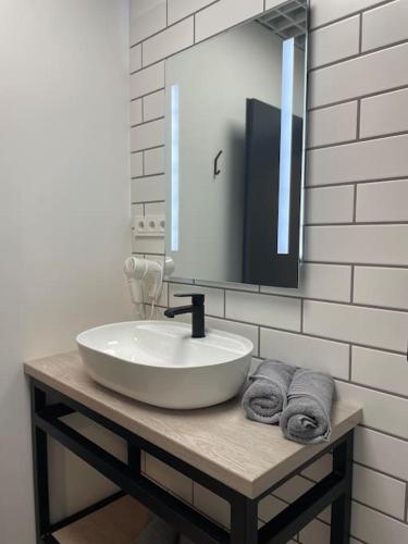 ein Badezimmer mit einem Waschbecken, einem Spiegel und Handtüchern in der Unterkunft Apartment Loftas13-7 in Kretinga