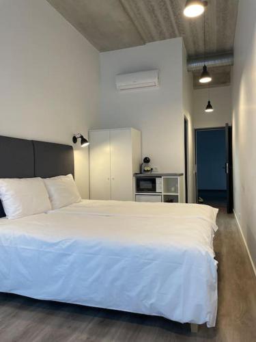 1 Schlafzimmer mit einem großen weißen Bett und einer Küche in der Unterkunft Apartment Loftas13-7 in Kretinga