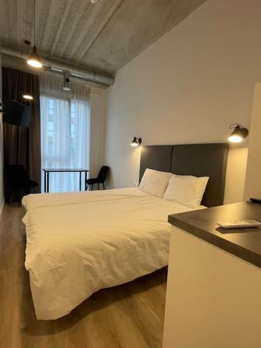 ein Schlafzimmer mit einem weißen Bett und einem Tisch in der Unterkunft Apartment Loftas13-7 in Kretinga