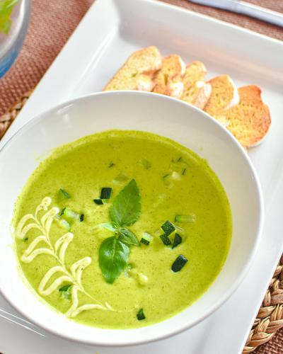 a bowl of broccoli soup on a plate with bread at Los Vados Hotel in Managua