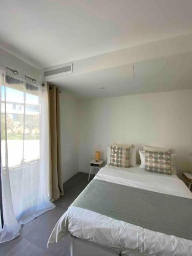 une chambre blanche avec un grand lit et une fenêtre dans l'établissement Maison Rayon de soleil, à Opio