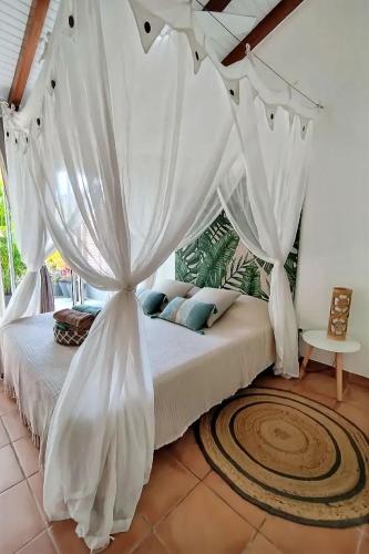 sypialnia z dużym łóżkiem z białymi zasłonami w obiekcie Ti Grounouy w mieście Le Diamant