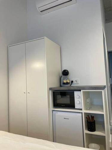 a white kitchen with a microwave and a cabinet at Apartment Loftas13-5 in Kretinga