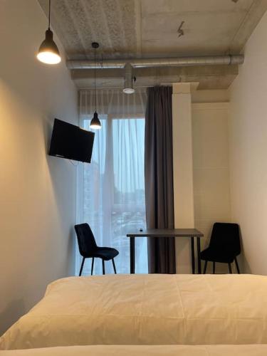 a bedroom with a bed and two chairs and a table at Apartment Loftas13-5 in Kretinga