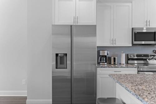 a kitchen with white cabinets and a stainless steel refrigerator at Luxury 2 bedrooms, 2.5 baths in Lawrenceville