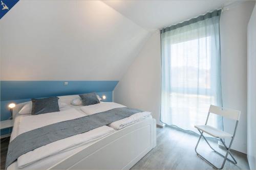 ein Schlafzimmer mit einem Bett, einem Stuhl und einem Fenster in der Unterkunft Ferienanlage Sonneninsel Haus Himmelblau Obergeschoss in Loddin