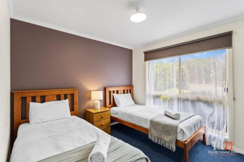 two beds in a room with a window at Phillip Island Family Resort 2Bdr in Cowes