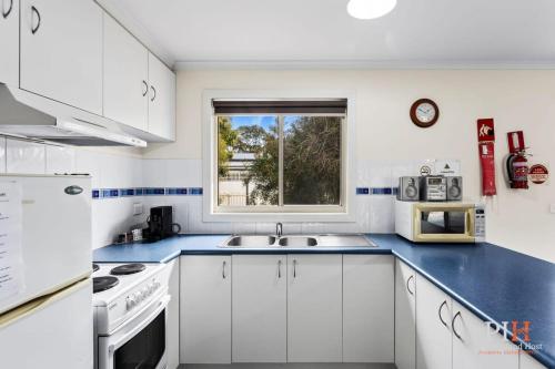 a white kitchen with a sink and a window at Phillip Island Family Resort 2Bdr in Cowes