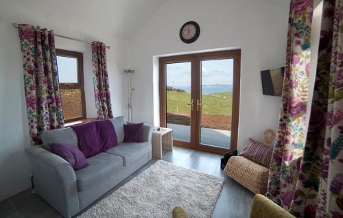 a living room with a couch and a clock on the wall at Stable Cottage - Kinbane Self Catering Cottages in Ballintoy