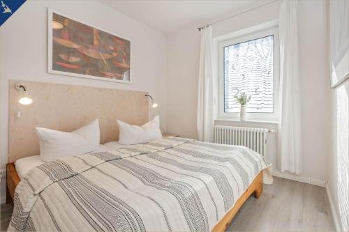 ein weißes Schlafzimmer mit einem Bett mit gestreifter Decke in der Unterkunft Ferienanlage Seeblick Kunstquartier in Ostseebad Koserow