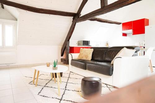 a living room with a black leather couch and a table at Chalet Lutétia, SPA & confort in Cormeilles-en-Parisis
