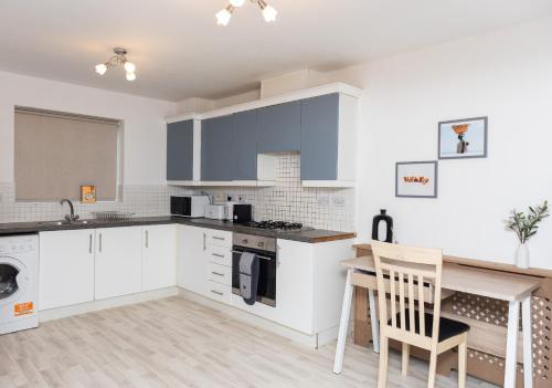 a kitchen with white cabinets and a wooden table at Caasi home Gorton Manchester in Manchester