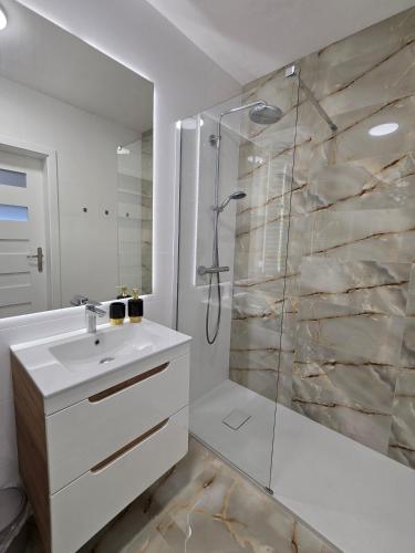 a white bathroom with a shower and a sink at Ekskluzywny apartament + garaż in Krakow