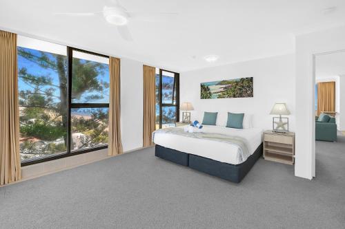 a bedroom with a large bed and large windows at Albatross North Apartments in Gold Coast