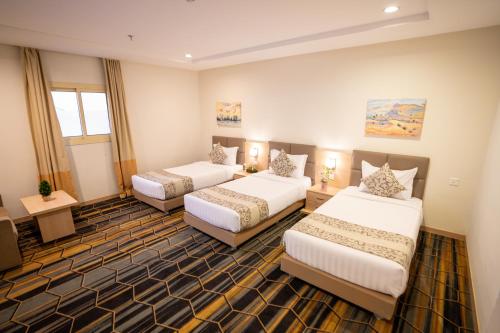 a hotel room with three beds in a room at فندق دار لمار in Makkah