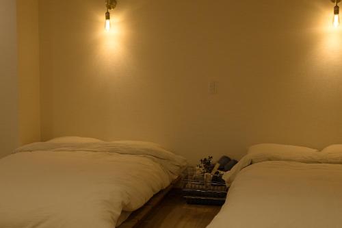 a bedroom with two beds and lights on the wall at 尾道stay源 -MINAMOTO- in Kaneyoshi