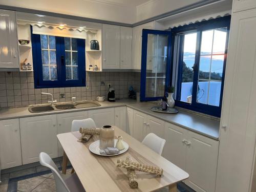 a kitchen with white cabinets and a table with chairs at Giannis & Maria Sunset House in Lagoúdi Zía