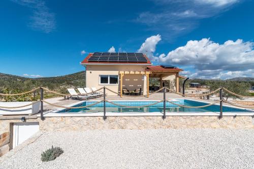 a house with a pool and a house with solar panels at Holiday house OLIVE LAND in Gustirna