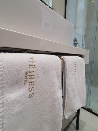 un asciugamano bianco appeso a un lavandino in bagno di HEIRESS Hotel a Sarandë