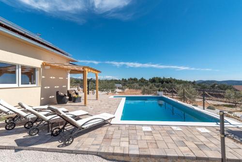 a villa with a swimming pool and a house at Holiday house OLIVE LAND in Gustirna