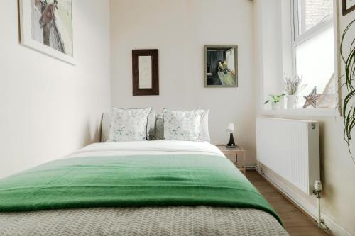 a bedroom with a bed with a green blanket at Arty Escape in Central London - Zone 2 in London