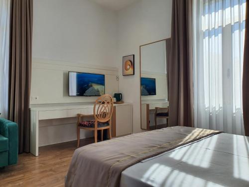 a bedroom with a bed and a desk and a chair at HEIRESS Hotel in Sarandë