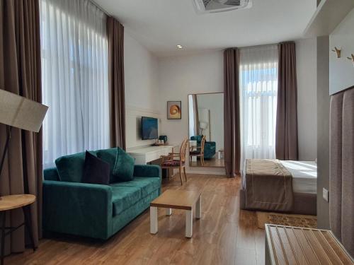 una camera d'albergo con un divano verde e un letto di HEIRESS Hotel a Sarandë