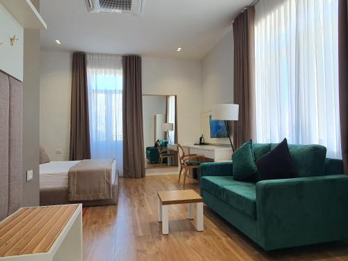 a hotel room with a green couch and a bed at HEIRESS Hotel in Sarandë