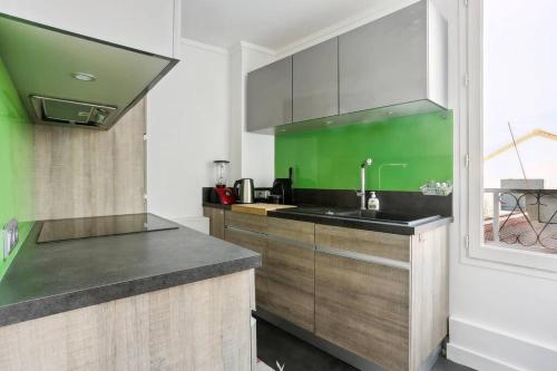 - une cuisine avec un évier et un mur vert dans l'établissement Appart hyper centre Rueil rénové !, à Rueil-Malmaison