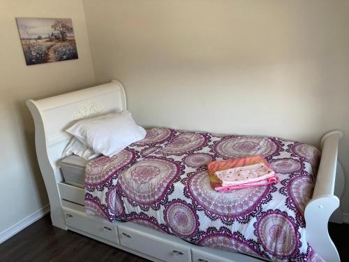 Dormitorio pequeño con cama blanca con manta morada en Gorgeous Home, en Brampton